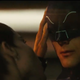 Selina Kyle caresses the blue mask of Adam West's 1966 Batman on a rooftop during the sunrise.